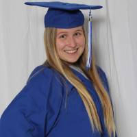 single girl poses in cap and gown blue
